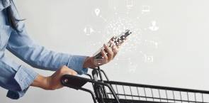 Frau mit Einkaufswagen und Smartphone inklusive Multichannel-Icons 