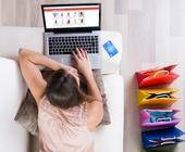 Junge Frau auf Sofa beim Online-Shopping mit Laptop