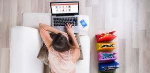 Junge Frau auf Sofa beim Online-Shopping mit Laptop 