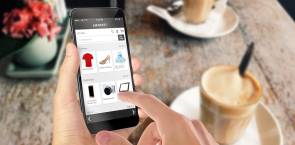 Online-Shopping mit Smartphone. Schreibtisch mit Kaffee im Hintergrund.  