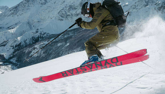 Skifahrer mit roten Ski bei der Abfahrt 