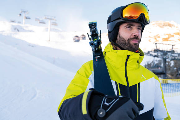 Mann mit Ski auf Piste