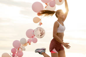 Frau läuft mit vielen Luftballons 