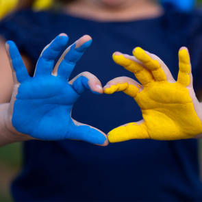 eine blaue und eine gelbe Hand formen ein Herz 