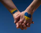 Zwei gefasste Hände mit der Ukraine-Flagge