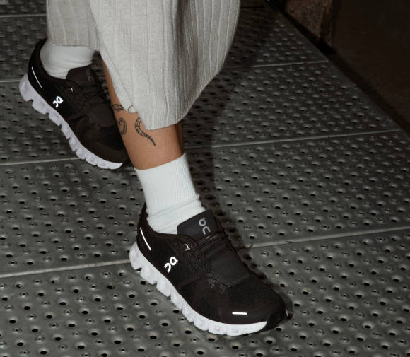 Tätowierter Frauenunterschenkel mit On-Schuh 