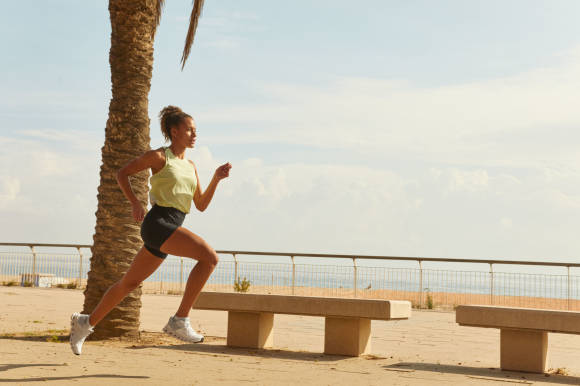 Frau läuft an Strandpromenade mit Palme 