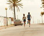 Zwei Läufer laufen auf Straße mit Palmen