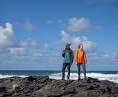 zwei Menschen am Meer mit Outdoor-Kleidung