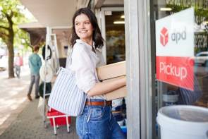 Frau geht in Paketschop mit Paketen in der Hand 