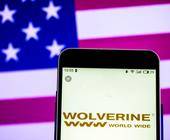 Logo von Wolverine World Wide mit US-Flagge im Hintegrund