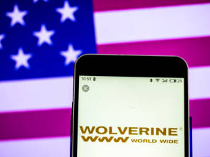Logo von Wolverine World Wide mit US-Flagge im Hintegrund 