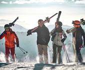 Menschen im Schnee mit Ski über den Schultern