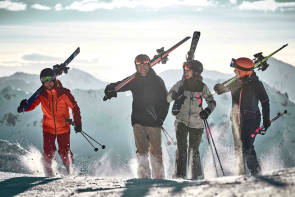 Menschen im Schnee mit Ski über den Schultern 