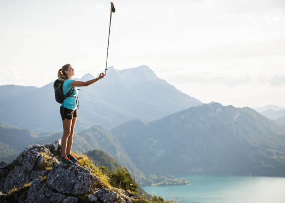 Frau auf Berggipfel mit Stock in der Hand 