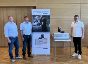 Drei Personen vor Schild 