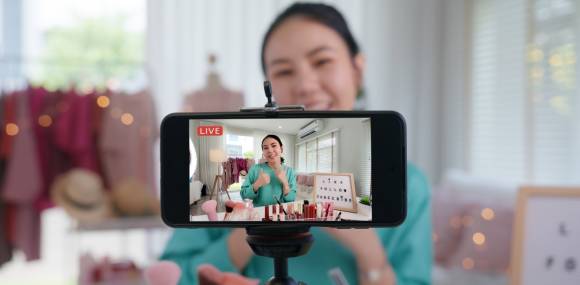 Junge Frau macht Live Shopping mit Smartphone