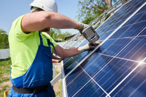 Mann bohrt Löcher in Photovoltaik-Anlage 