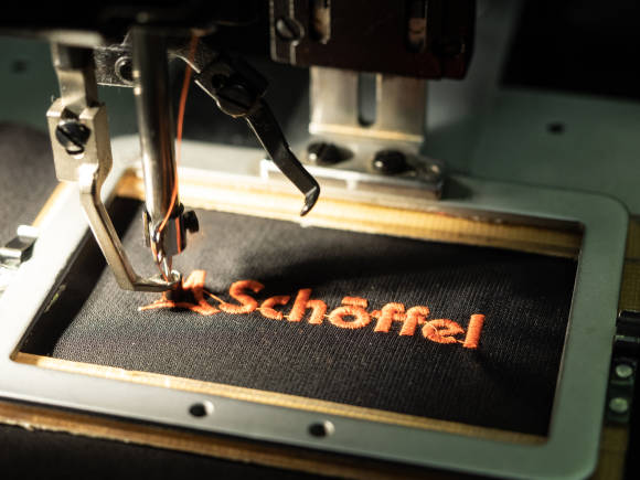 Stickereimaschine stickt Schöffel-Logo 