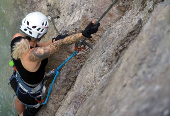 Frau mit Tattoos klettert am Berg 