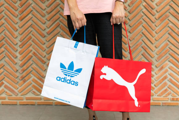 Person mit Adidas- und Puma-Tüte 