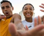 zwei lachende Sportler mit Hoka-T-Shirts