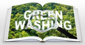 aufgeschlagenes Buch mit Green Washing Schriftzug unter Lupe 