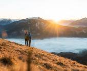 zwei Menschen beobachten den Sonnenaufgang in den Bergen