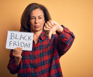 Frau hält Black Friday Schild und macht den Daumen nach unten