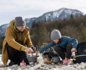 Mann mit Kind in den Bergen beim Kochen