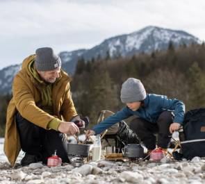 Mann mit Kind in den Bergen beim Kochen 