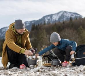 Mann mit Kind in den Bergen beim Kochen 