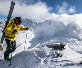 Mann mit Tourenski auf Bergipfel im Schnee