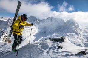 Mann mit Tourenski auf Bergipfel im Schnee 