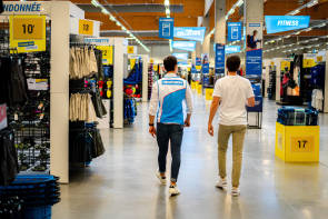 Decathlon-Mitarbeiter läuft durch Filiale mit Kunden 