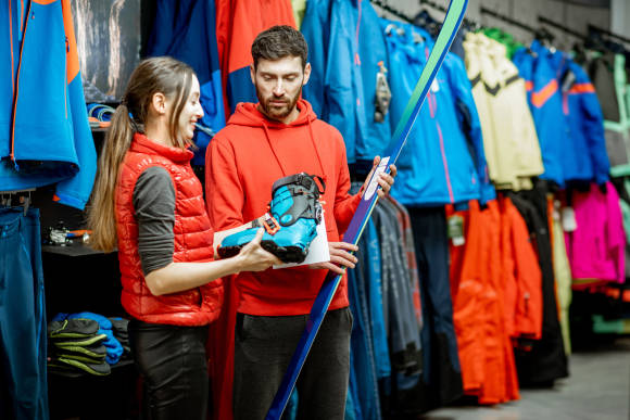 Sportfachhändler bei der Beratung beim Kauf von Wintersportartikeln 