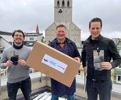 drei Männer mit P.A.C.-Paket über den Dächern Münchens