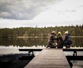 drei Menschen an einem See mit Outdoor-Kleidung