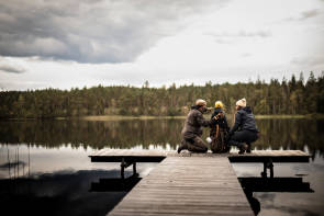 drei Menschen an einem See mit Outdoor-Kleidung 