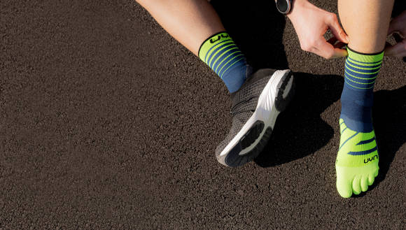 Person mit Sportsocken zieht Laufschuhe an 