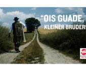 Mann mit bayerischer Tracht läuft mit Blasinstrument auf Feldweg