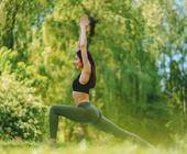 Frau mit Sportbekleidung stretcht sich in grüner Natur