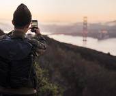 Mann fotografiert mit Handy die Golden Gate Bridge