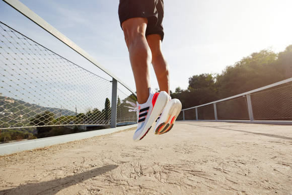 Läufer springt hoch mit Adidas-Schuhen 