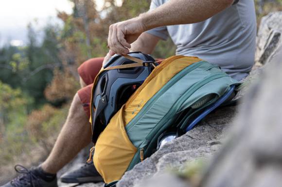 Mann mit Rucksack sitzt auf Felsen 