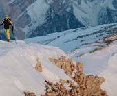 Zwei Skitourengeher bei Aufstieg vor Bergkulisse.