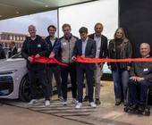 Sebastian Schaller, Geschäftsführer Oberalp Deutschland (3. v. l.), und Hubert Link (4. v. l.), Director Audi Charging Hub, schneiden das rote Band durch, um die neue Schnellladestation offiziell zu eröffnen.