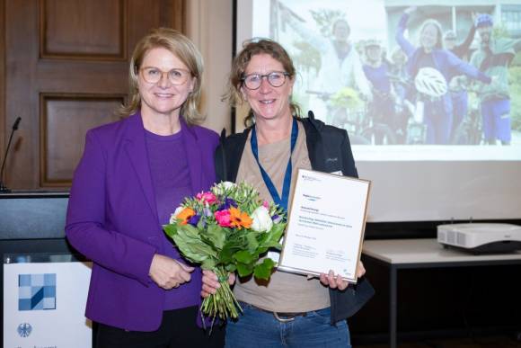 Sabine Porschmann, Parlamentarische Staatssekretärin bei der Bundesministerin für Wohnen, Stadtentwicklung und Bauwesen, übereicht Kerstin Mommsen, Vaude Unternehmenskommunikation, den Bundespreis. 