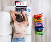 Frau liegt auf dem Sofa und surft im Webshop